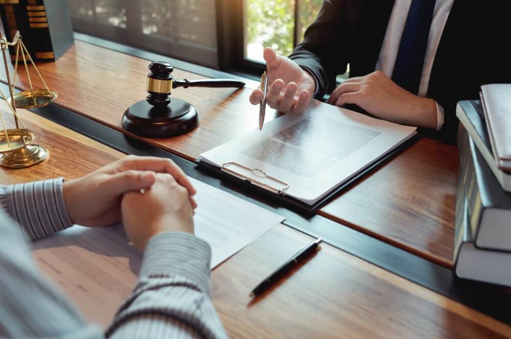 Attorney consulting with client over legal documents at a desk, featuring a gavel and scales of justice, relevant to Maryland real estate and estate planning law.