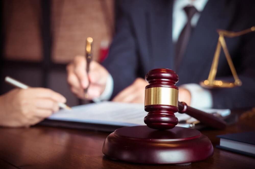 Gavel on a table with a lawyer signing documents and discussing legal matters, emphasizing estate planning and probate services.
