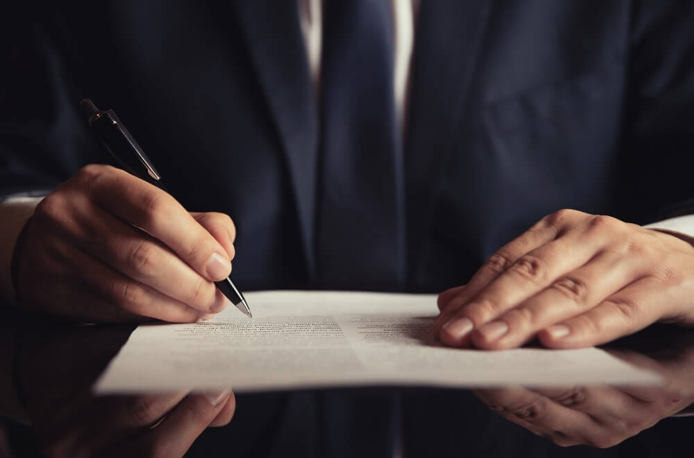 Person in a suit signing legal documents, symbolizing tax sale foreclosure processes in Maryland.