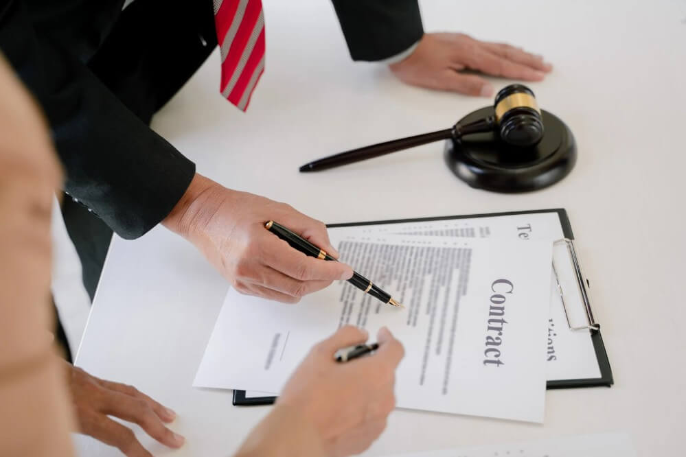 Hands signing a contract with legal documents and a gavel, representing legal services and estate planning in Maryland.