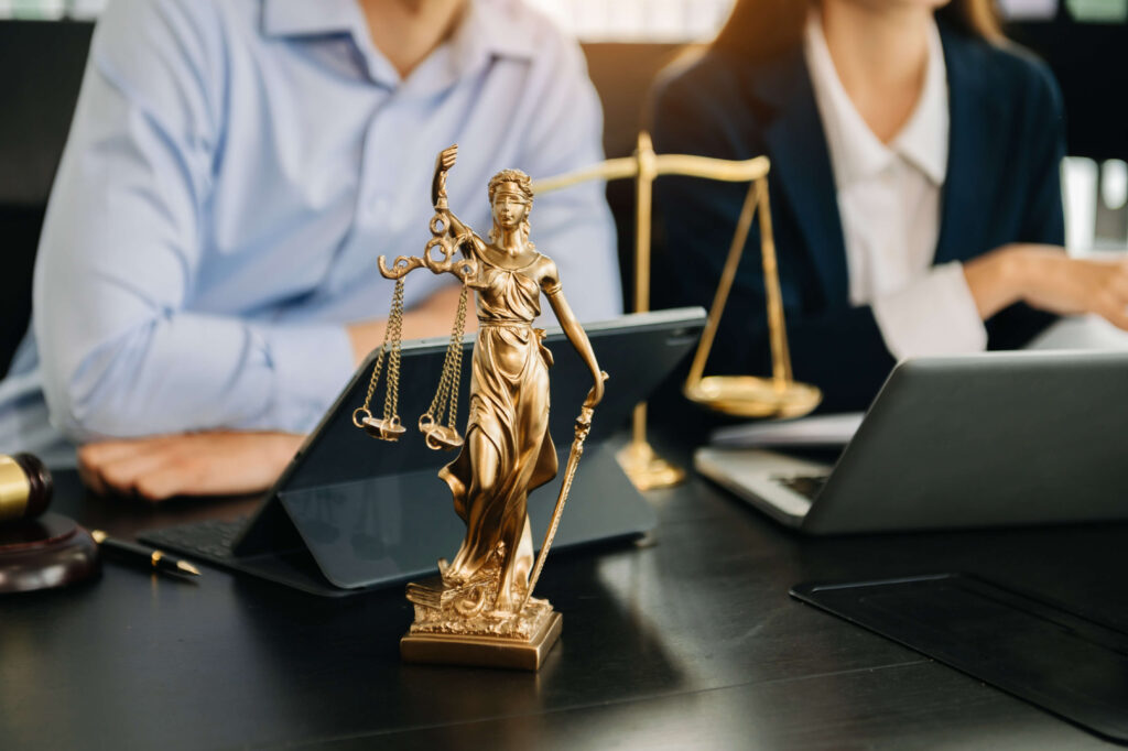 Lawyers discussing legal documents at a desk with a Lady Justice statue and scales, symbolizing legal guidance and estate planning in Maryland.